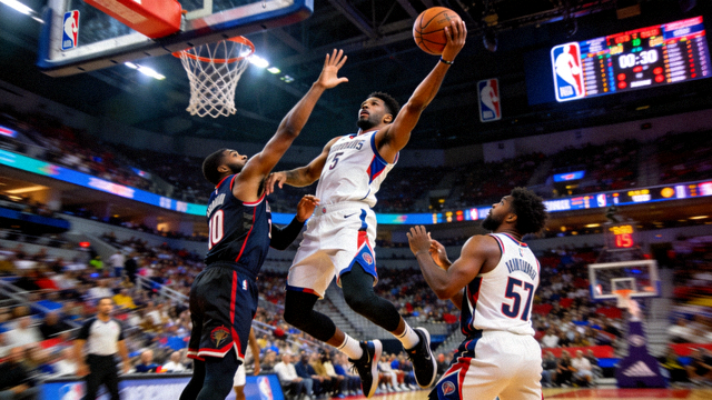 NBA职业篮球比赛精彩瞬间，球员高高跃起准备投篮，对手防守严密